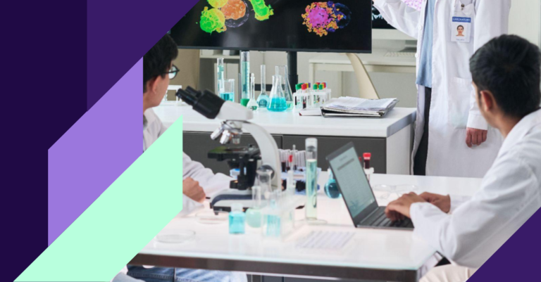 Researchers in a laboratory reviewing molecular imaging data on screen while working with a microscope and laptop